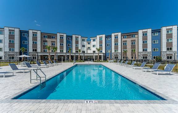 A swimming pool in front of a row of apartment buildings.