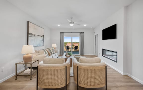 A living room with two chairs in the foreground looking forward onto patio windows.