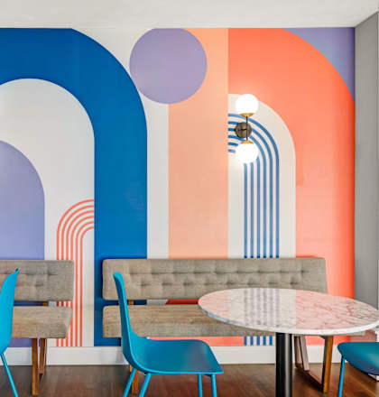 a restaurant with blue chairs and tables and a colorful wall with arches