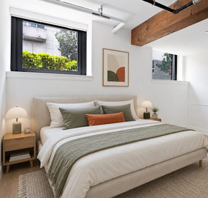 A bedroom with a bed, nightstands, and a painting on the wall.