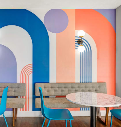 a restaurant with blue chairs and tables and a colorful wall with arches