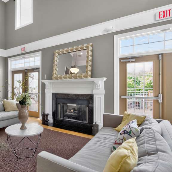 A living room with a grey couch, a fireplace, and a mirror on the wall.