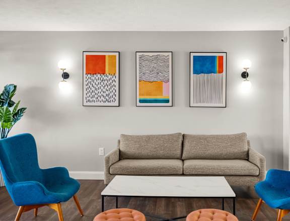 a living room with a couch and chairs and paintings on the wall