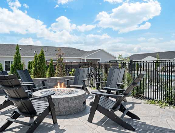A fire pit surrounded by chairs in a backyard.