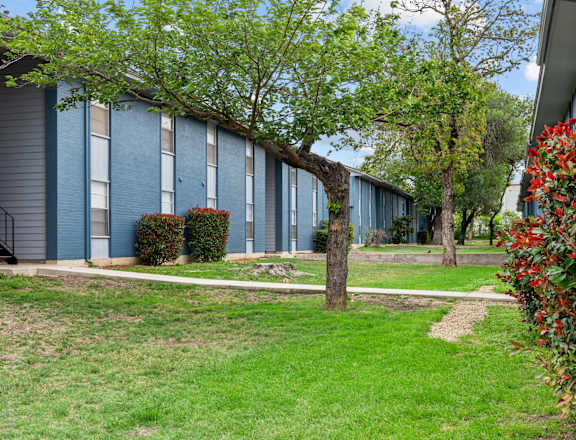 a building with blue siding and a tree in front of it  at Sunset Heights, San Antonio, TX