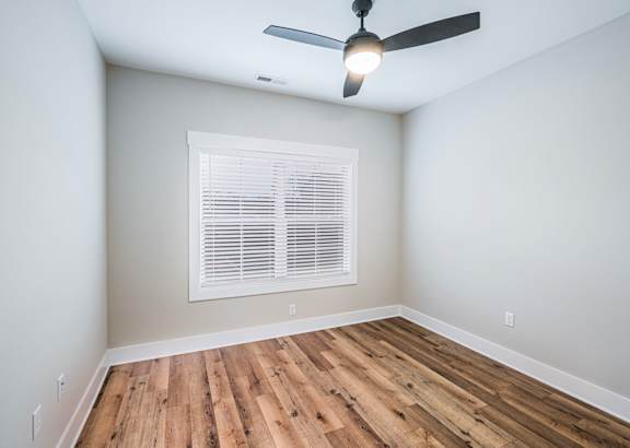 A room with a ceiling fan and a window with blinds.