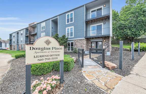 A sign for Douglas Place Apartments of Townhomes is in front of a building.