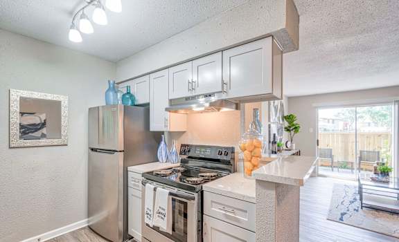 A kitchen with a stainless steel refrigerator, oven, and cabinets.