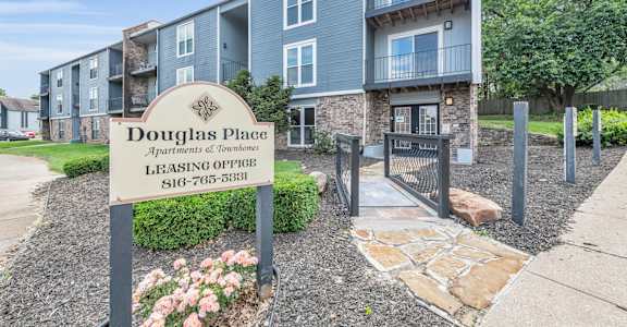 A sign for Douglas Place Apartments of Townhomes is in front of a building.