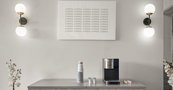 a cupboard with a coffee maker and a tablet on it in a living room