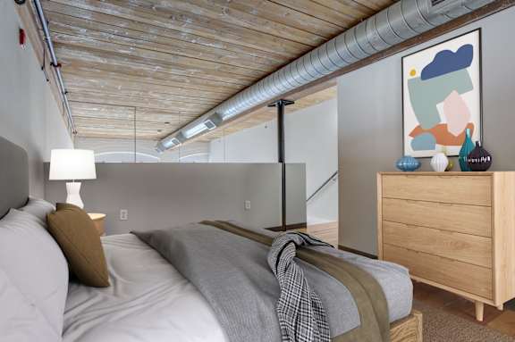 a bedroom with a bed and a dresser in a loft