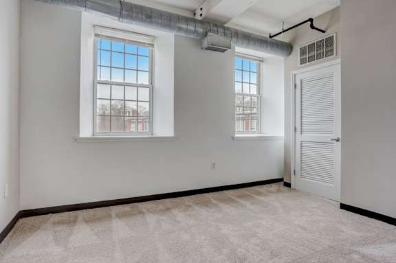 an empty living room with three windows and a door