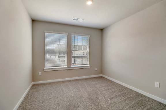 A room with a carpeted floor and a window with blinds.