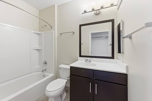A white toilet sits next to a white bathtub in a bathroom.