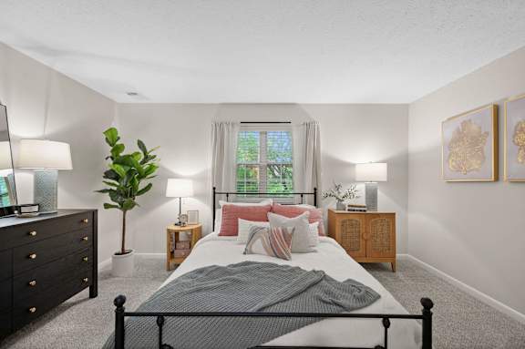 A bedroom with a bed, nightstands, and a plant.