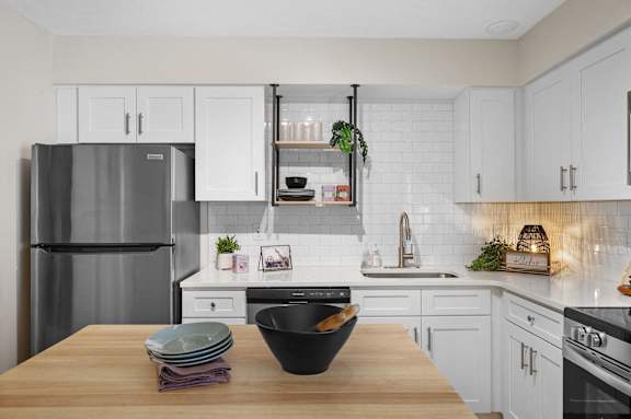 A kitchen with a refrigerator, oven, and sink.