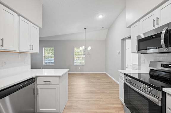 A kitchen with white cabinets and black appliances.