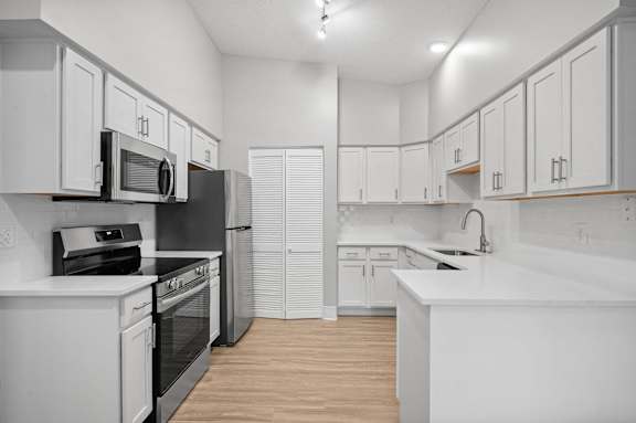 A kitchen with white cabinets and appliances.