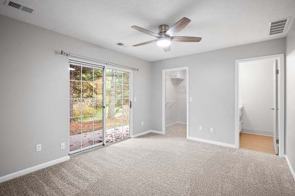 A room with a ceiling fan and sliding glass doors.