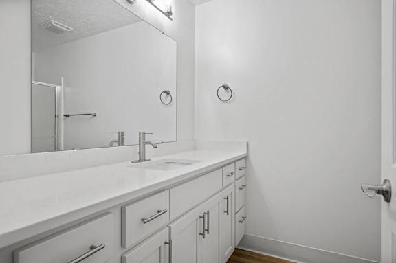 A white bathroom with a sink and mirror.