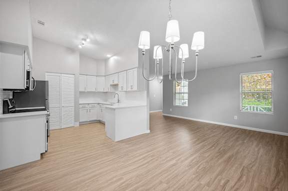 A modern kitchen with white cabinets and a wooden floor.