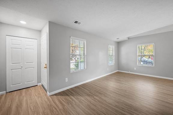 A room with a white door and two windows with blinds.