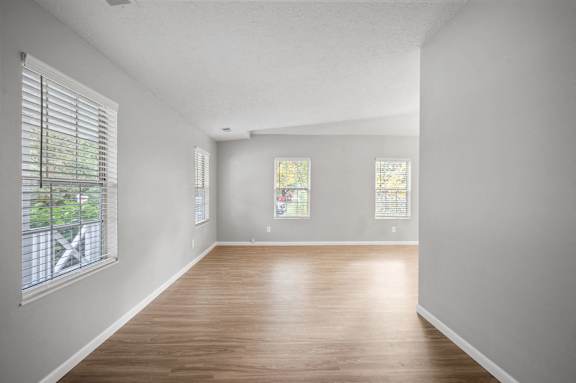 A room with wooden floors and two windows.