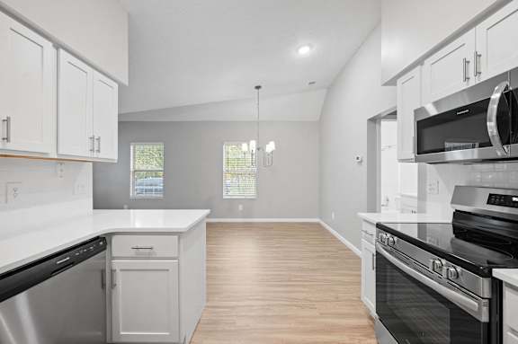 A kitchen with white cabinets and black appliances.
