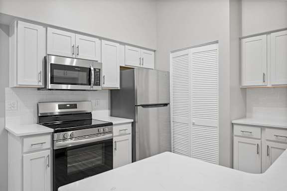 A kitchen with white cabinets and appliances.
