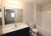 Thumbnail 11 of 14 - A bathroom with a white sink, toilet, and bathtub.