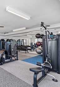 A spacious gym with a variety of equipment including treadmills, weights, and a television.