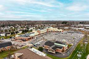 A parking lot is in front of a building with a yellow roof.