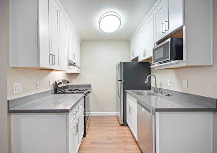 an empty kitchen with white cabinets and stainless steel appliances