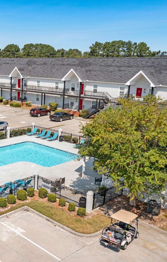 A large swimming pool surrounded by a fence and a playground.