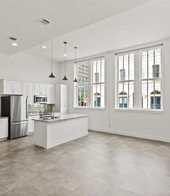 A kitchen with a refrigerator, sink, and cabinets.