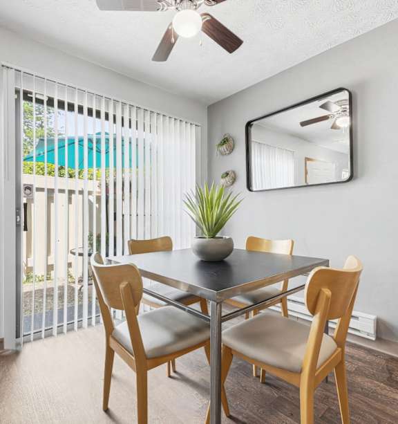 A dining room with a table and chairs and a ceiling fan.