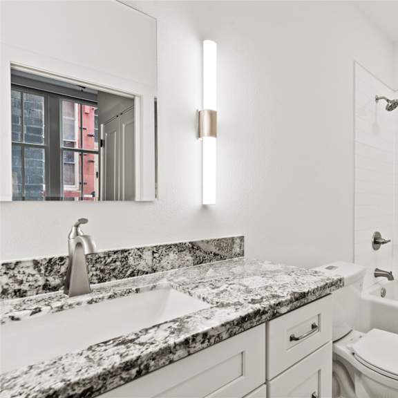 A modern bathroom with a marble countertop and a large mirror.