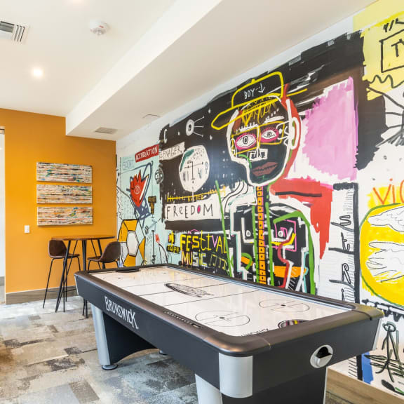 a game room with a pool table and graffiti on the wall