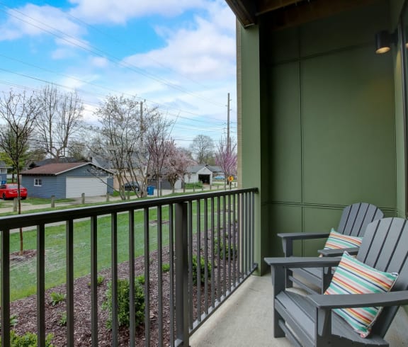 a balcony with two chairs and a view of a yard and houses