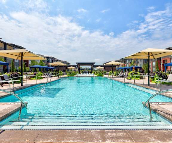 A large outdoor swimming pool surrounded by lounge chairs and umbrellas.