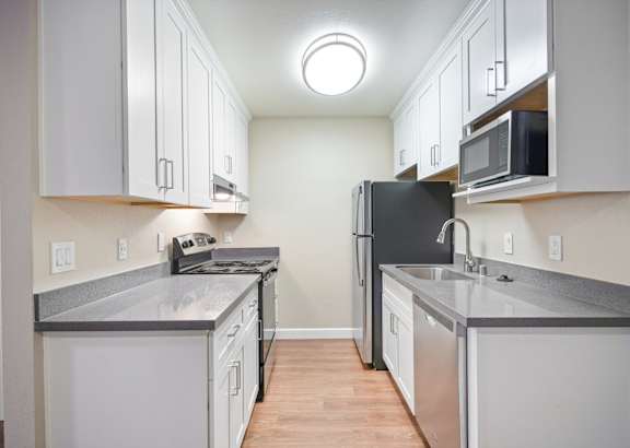 an empty kitchen with white cabinets and stainless steel appliances