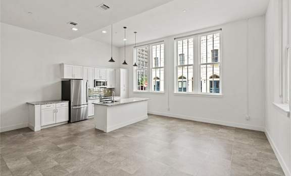 A kitchen with a refrigerator, sink, and cabinets.