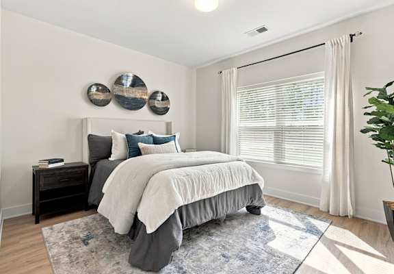 A bed with a white sheet and orange pillows is in the image.