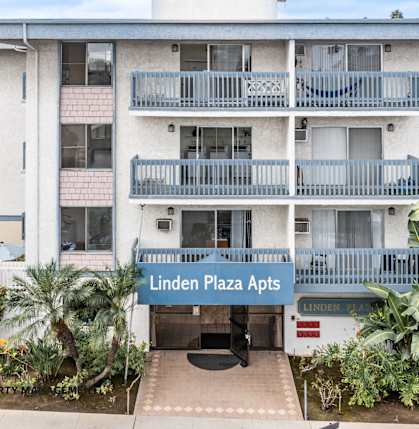 Linden Plaza Apts is a white apartment complex with a blue sign in front.