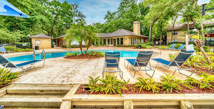 A pool surrounded by chairs and plants with a house in the background.