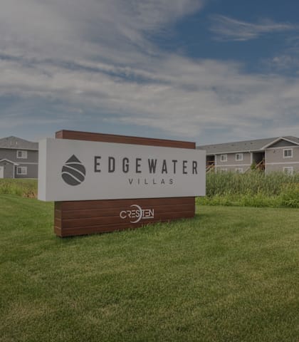 A sign for Edgewater Village stands in a grassy field.