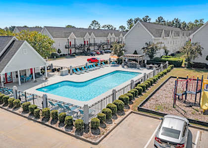A swimming pool surrounded by a black fence and bushes.