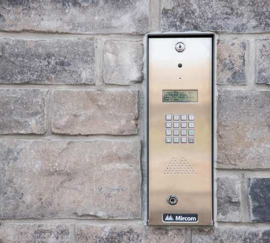 a stainless steel elevator control panel on a brick wall