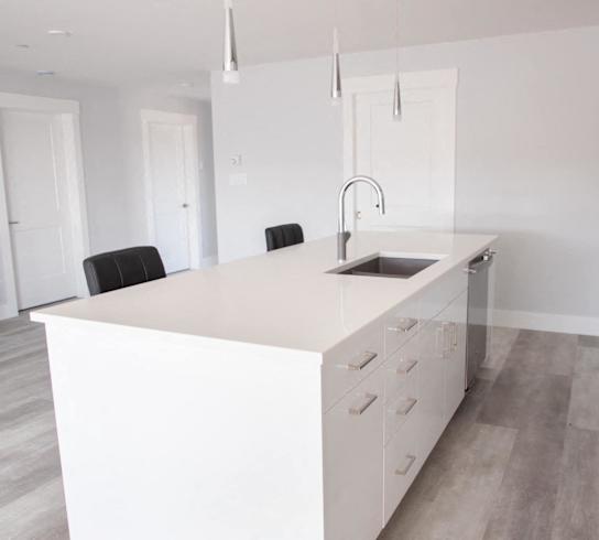 a white kitchen with a large island and a sink