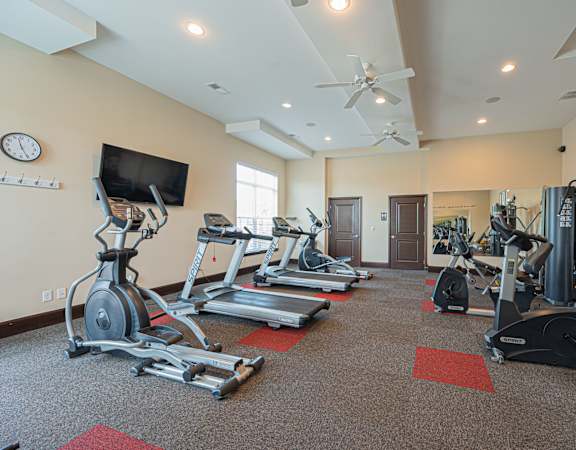 a gym with treadmills and weights and a tv